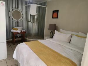 um quarto com uma cama branca e um espelho em 19th on Bloekom Guesthouse em Secunda