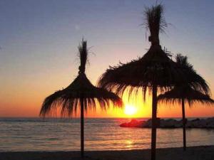 two straw umbrellas on the beach with the sunset at bayekou trapani in Trapani