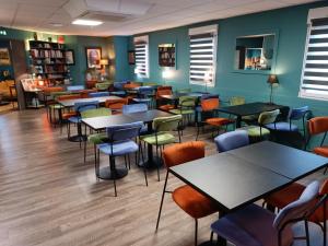 une salle avec des tables et des chaises dans une bibliothèque dans l'établissement Hôtel Kyriad Brive Ouest, à Brive-la-Gaillarde