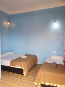 two beds in a room with a blue wall at JV Inn Perhentian in Kampong Pasir Hantu