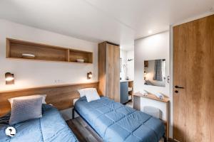 een slaapkamer met een blauw bed en een spiegel bij Camping Les Violettes in La Faute-sur-Mer