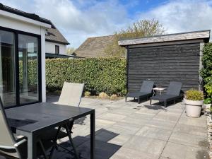 a patio with two chairs and a table and a fence at Vakantiehuis Huisje 31 Zoutelande in Zoutelande