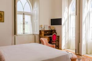 a bedroom with a bed and a desk and two windows at Torres da Vila in Anadia