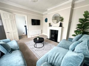 a living room with a blue couch and a table at The Capstone Retreat - Beautiful Detached Family Home By Coastline Retreats, Arcade Machine, Parking, BBQ in Bournemouth