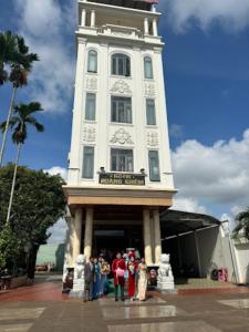 un grupo de personas parados frente a una torre del reloj en Hoàng Khiêm Hotel en Pleiku