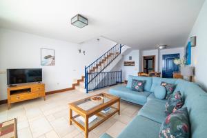 a living room with a blue couch and a tv at Brisa Marina in Puerto Calero