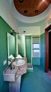 a green bathroom with a sink and a mirror at Botanique Hotel Vergani in Fara Gera dʼAdda