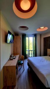 a bedroom with a bed and a desk and a television at Botanique Hotel Vergani in Fara Gera dʼAdda