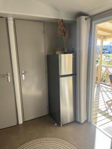 - une cuisine avec un réfrigérateur en acier inoxydable à côté d'une porte dans l'établissement Mobil home climatisé au calme et proche des activités LEGE CAP FERRET, à Lège-Cap-Ferret