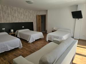 pokój hotelowy z 2 łóżkami i kanapą w obiekcie Noja Rooms w mieście O Pedrouzo