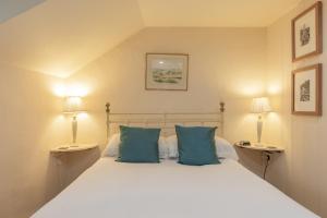a bedroom with a large white bed with blue pillows at Briar Cottage in Westleton