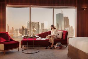 a woman sitting on a couch in a room with a window at Jumeirah Emirates Towers Dubai in Dubai