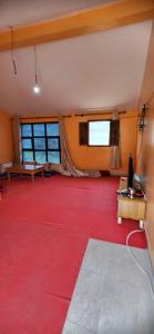 Großes Zimmer mit einem roten Boden und einem TV. in der Unterkunft Gite Aguelmous réservé aux familles 