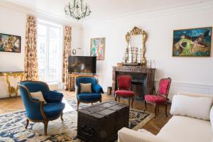 uma sala de estar com um sofá e cadeiras e uma televisão em Magnifique appartement au coeur de Versailles em Versailles