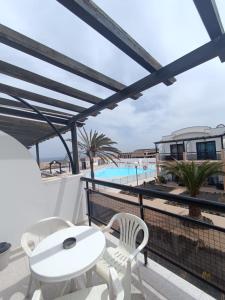 a balcony with a table and chairs and a pool at Apartamento SUMMER Complex Amaya Fuerteventura in Costa de Antigua