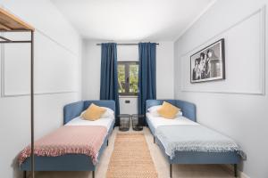 two beds in a room with blue chairs and a window at Villa Andy Rovinj in Rovinj