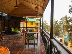 un balcone di una casa con tavolo e sedie di THEHIMALAYANLIVING WHISTLING PINES a Mukteshwar