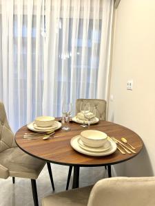 a wooden table with plates and wine glasses on it at Luxury RA Apartment in Oradea