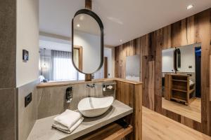 W łazience znajduje się umywalka i lustro. w obiekcie Hotel Eccher 3 stelle Superior w mieście Mezzana