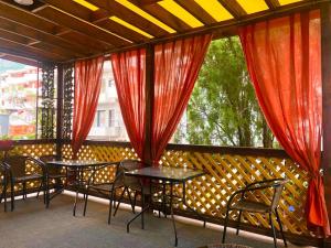 - un balcon avec deux tables et des chaises et des rideaux rouges dans l'établissement Apartments DS Club, à Budva