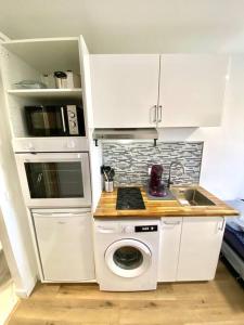 eine kleine Küche mit einer Waschmaschine und einem Waschbecken in der Unterkunft Cosy Studio neuf centre-ville in Orsay