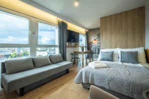 a bedroom with a bed and a couch and a table at WiguryTower Apartaments 98 in Łódź