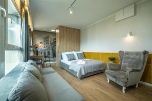 a bedroom with a bed and a couch and a chair at WiguryTower Apartaments 98 in Łódź