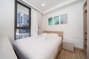 a white bedroom with a large bed and a window at Skypark Laguna BangTao Beach Apartment-Long Term Lease in Phuket Town