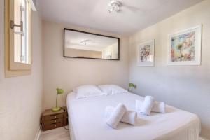 a bedroom with a white bed with a mirror on the wall at Duplex T3, terrasse 18m2 vue mer, proche plage in Le Lavandou