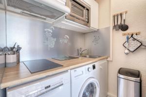 a kitchen with a washing machine and a sink at Duplex T3, terrasse 18m2 vue mer, proche plage in Le Lavandou