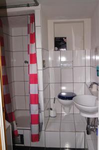 ein Bad mit einem roten und weißen Duschvorhang und einem Waschbecken in der Unterkunft Mitten im Garten in Friedland