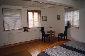 1 Schlafzimmer mit einem Bett, 2 Stühlen und Fenstern in der Unterkunft Mitten im Garten in Friedland