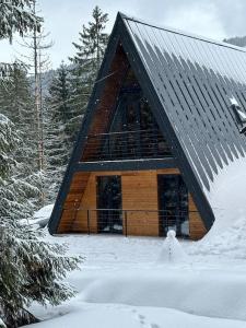 domek z bali na śniegu z drzewami pokrytymi śniegiem w obiekcie Tramonto Cabin w mieście Vartop