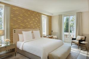 a bedroom with a large white bed and a chair at Grand-Hôtel du Cap-Ferrat, A Four Seasons Hotel in Saint-Jean-Cap-Ferrat