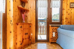 een kamer met houten wanden en een deur met een raam bij Trilo Luce della Paganella in Andalo