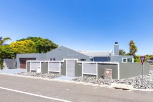 une maison blanche avec un tas de pierres à côté d'une rue dans l'établissement Family Home in West Beach, Blouberg, au Cap