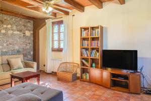 a living room with a television and a book shelf at Can Malràs in Massanas