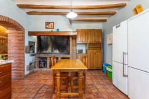 uma cozinha com uma mesa de madeira e uma lareira em Can Malràs em Massanas