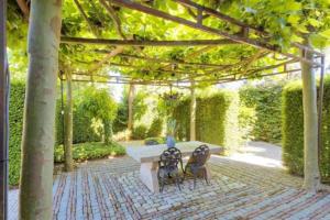 een patio met een tafel en stoelen in een tuin bij SpotElst vakantiehuis in Elst