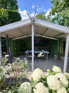 een paviljoen met een picknicktafel in een tuin bij SpotElst vakantiehuis in Elst