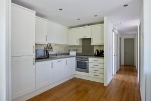 a kitchen with white cabinets and a wooden floor at Beckington Lodge in Beckington