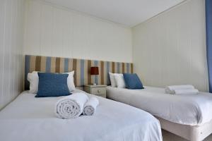 two beds in a white room with blue pillows at Beckington Lodge in Beckington