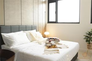 a white bed with a tray of food on it at Chambers Signature Suites, Kuala Lumpur in Kuala Lumpur