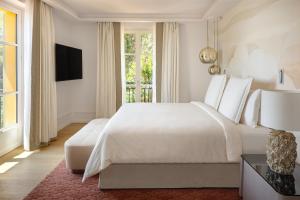 a white bedroom with a large bed and a window at Grand-Hôtel du Cap-Ferrat, A Four Seasons Hotel in Saint-Jean-Cap-Ferrat