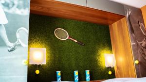 een spiegel met een tennisracket op een groene muur bij Boutique Hotel Kronenhof in Zürich