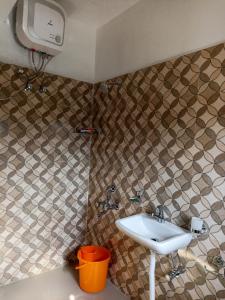 Łazienka z umywalką i ścianą wyłożoną kafelkami w obiekcie HILLSCAPE w mieście Czerapuńdżi