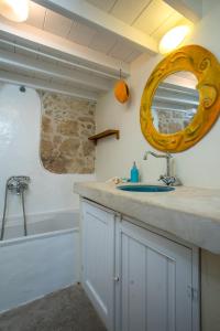 ein Bad mit einem Waschbecken und einem Spiegel in der Unterkunft Mandarin traditional house with outdoor jacuzzi in Koskinou