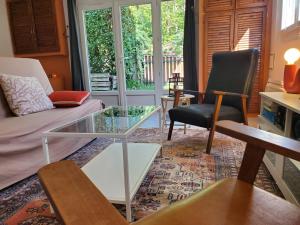 a living room with a couch and a glass table at Au Petit Sequoia - Appt avec vue montagne in Saint-Mamet +3 photos