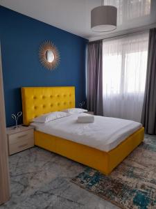 a bedroom with a yellow bed and a blue wall at Apartament Palma 2 Stefan Resort in Mamaia Sat/Năvodari