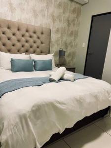ein Schlafzimmer mit einem großen weißen Bett mit blauen Kissen in der Unterkunft Cozy Escape in Windhoek